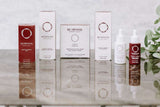 Morphiya Genesis Formula skincare product set with red and white boxes and dropper bottles featuring logo and text on a reflective surface