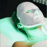 PRO by Déesse PRO LED Mask | Professional LED Light Therapy white flexible silicone facial mask emitting green light on person