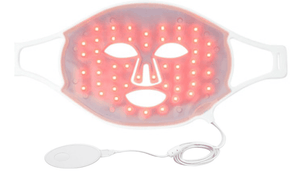 Flexible white silicone Déesse Pro LED Mask with red glowing LED lights for facial light therapy and USB cable attached.